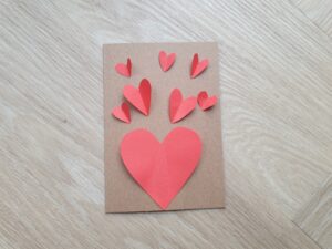 Geknutselde valentijnskaart met papieren hartjes erop geplakt