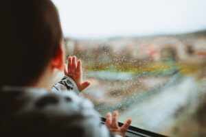 Kind voor het raam met regen