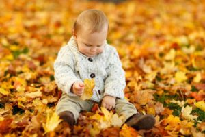 Kindje tussen de herfstbladeren